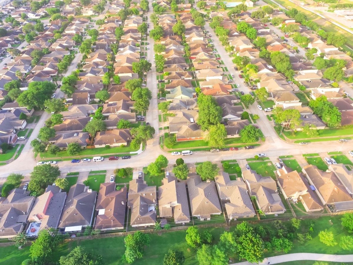 Aerial view huge park near residential houses in Houston, Texas, USA. Green urban recreation with long pathway surrounds with green tree. Tightly packed homes neighborhood and driveways flyover